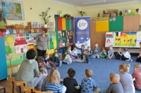 Na pierwszym planie grupa dzieci siedząca w kręgu i słuchająca prowadzącej, która wskazuje na mapę Szwecji zawieszoną na kolorowej ścianie w Sali przedszkola. W tle wnętrze sali przedszkolnej oraz baner Punktu Informacji Europejskiej Europe Direct w Olsztynie.