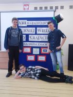 Uczniowie ze Szkoły Podstawowej nr 5 w Ostródzie na tle plakatu reklamującego VIII Wojewódzki Turniej Wiedzy o Krajach Anglojęzycznych