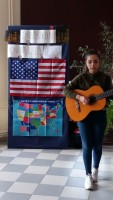 Na zdjęciu uczennica SP 2 , podczas mini recitalu odbywającego się w przerwie konkursu. W tle baner z flagą i mapą Stanów Zjednoczonych