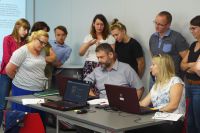 2019-06-28_wystartuj z video_4 - Uczestnicy skupieni nad jednym z komputerów słuchają komentarza trenerki (Agaty Warywody)