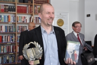 Micha Olszewski w lewej rce trzyma ksik, za ktr dosta nagrod pt.: 