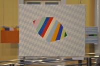 Na zdjciu jedna z prac Ashley'a Collina - obraz prezentowany w Galerii. Obraz przedstawia ksztat z kolorowych pasw namalowany na szaro-biaym tle.