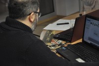 Ralf Maindl siedzi przy komputerze i oglda stare zdjcie z trzema onierzami.