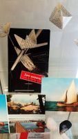 Cz ekspozycji eglarskiej: dwie kolorowe pocztwki z aglowcami, kolorowa pocztwka z pla jeziorn, kolorowa pocztwka z pomostem na jezierze oraz ksika kapitana Tomasza Cichockiego „Zew oceanu”.