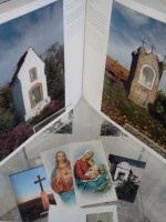 Fragment ekspozycji na jednej z pek: potwarta ksika z fotograficznymi reprodukcjami dwch nietypowych murowanych kapliczek oraz dwa obrazki religijne - wizerunki Serca Jezusa oraz Matki Boej z Dziecitkiem.