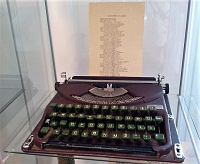 Fragment wystawy w witrynie: tradycyjna maszyna do pisania oraz przyklejona na szybie odbitka wiersza „Lokomotywa socjalizmu”.